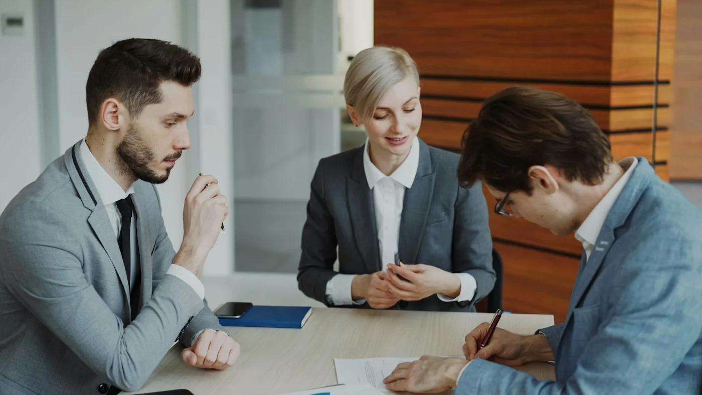 Três profissionais reunidos ao redor de uma mesa.